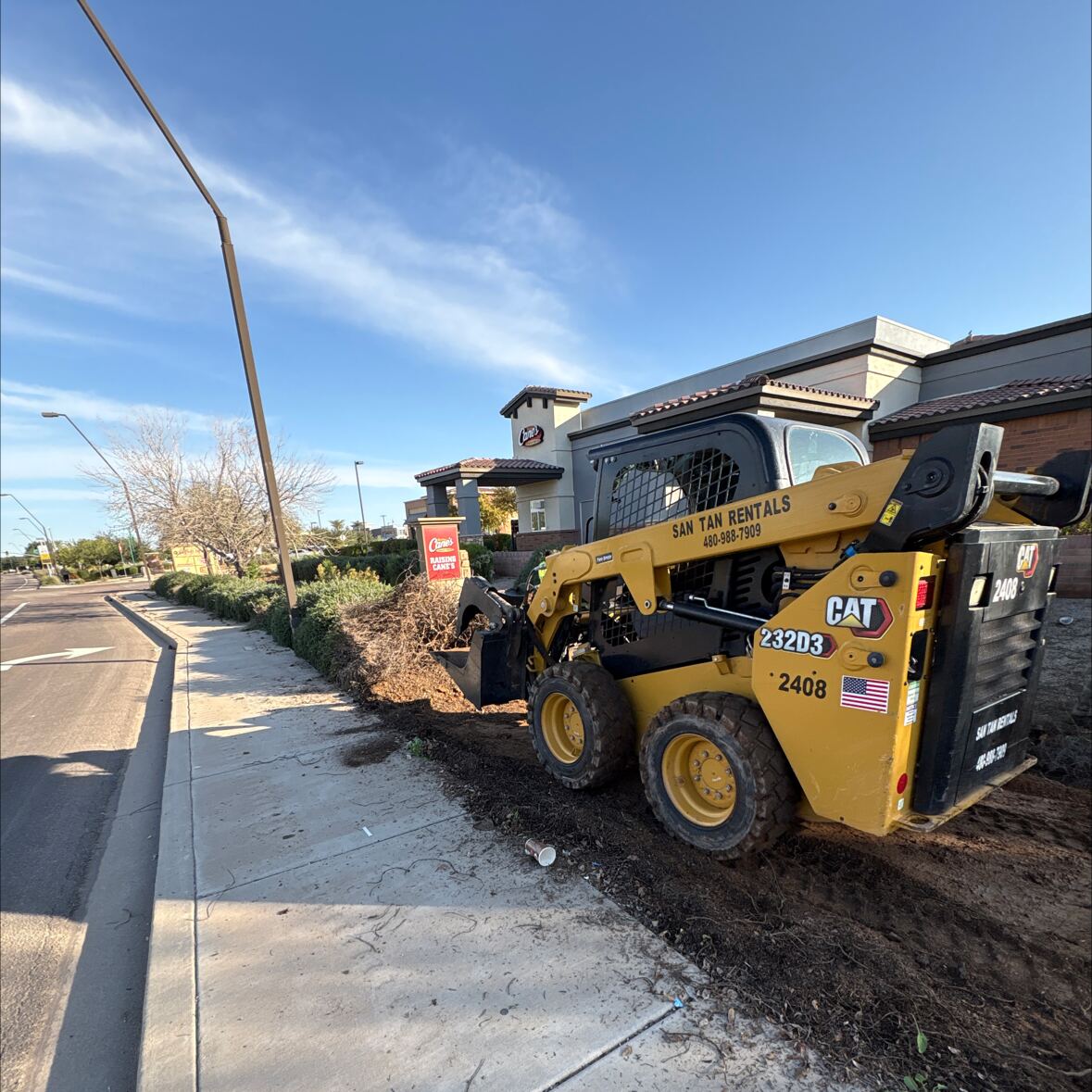 Skid steer clearing old landscaping before renovation