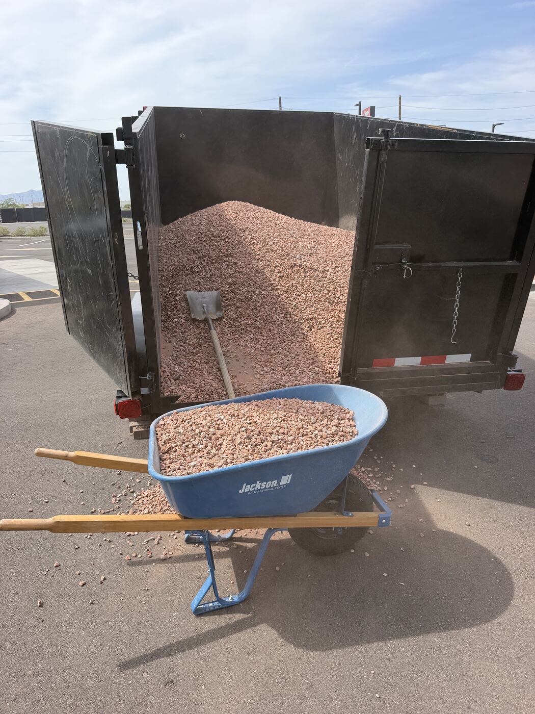 Crew loading decomposed granite by wheelbarrow from a dump trailer